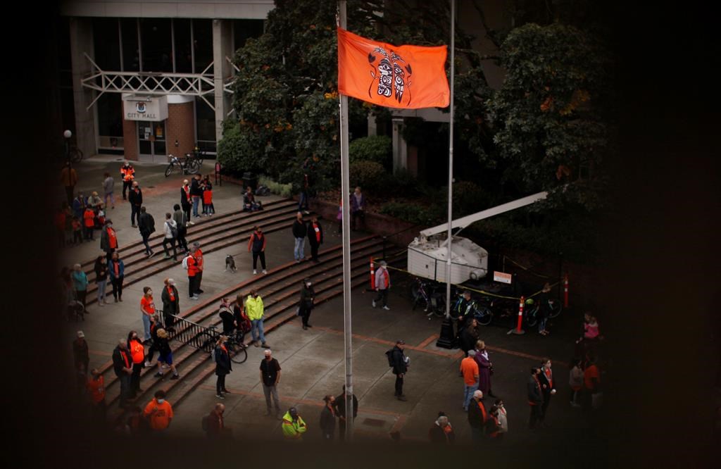 A ceremonial flagged is raised as people attend the Xe xe Smun’ eem-Victoria Orange Shirt Day Every Child Matters ceremony to honour victims of the Canadian Indian residential school system while at Centennial Square in Victoria, Thursday, Sept. 30, 2021.