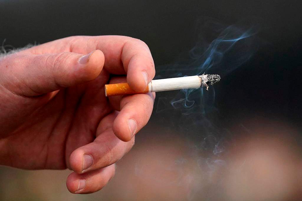 A man holds a lit cigarette.