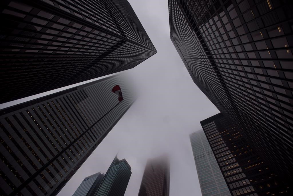 The Canadian flag blows in the wind in the heart of the financial district in Toronto on June 27, 2018. THE CANADIAN PRESS/Tijana Martin.
