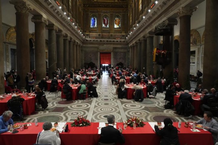 People sit at a Christmas day soup kitchen for fragile people, the poor, the homeless, and asylum seekers, set by the Sant’Egidio Community, at the Santa Maria in Trastevere Basilica in Rome, Saturday, Dec. 25, 2021.