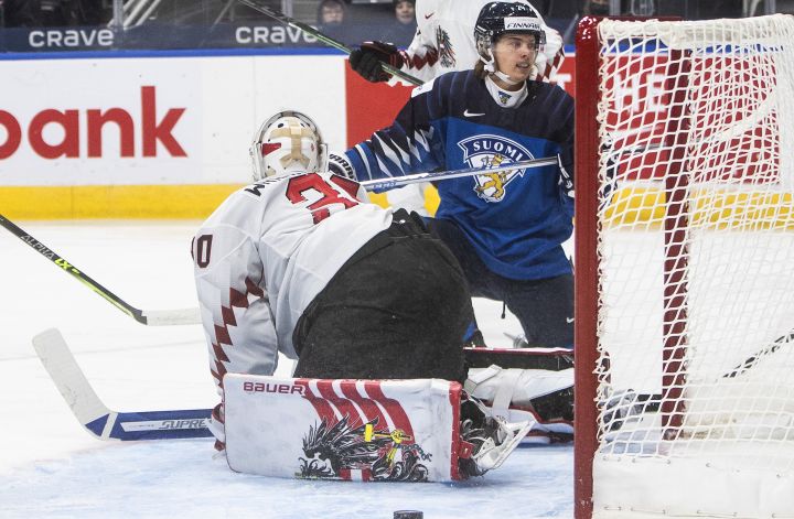 Finland’s Ville Koivunen (24) scores a goal on Austria’s goalie Sebastian Wraneschitz (30) during first period IIHF World Junior Hockey Championship action in Edmonton, Monday, Dec. 27, 2021.