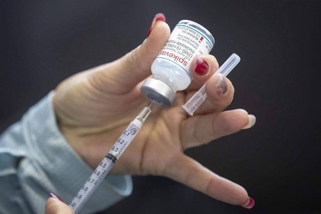 A person draws out Moderna vaccine during a drive through COVID-19 vaccine clinic at St. Lawrence College in Kingston, Ont., Sunday, Jan. 2, 2022. 