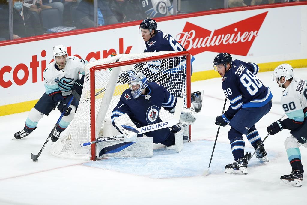 Seattle Kraken’s Jordan Eberle (7) looks for Marcus Johansson (90) as he attempts to make a pass in front of Winnipeg Jets goaltender Eric Comrie (1) during second-period NHL action in Winnipeg on Thursday, Feb. 17, 2022. THE CANADIAN PRESS/John Woods