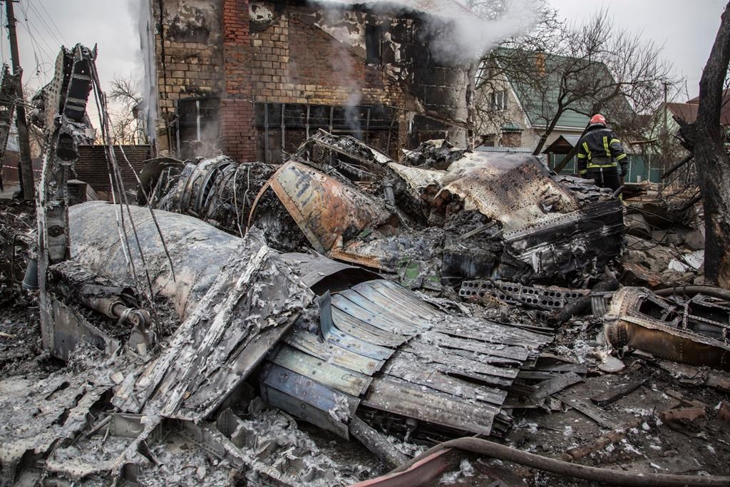 A Ukrainian firefighter walks between fragments of a downed aircraft in Kyiv, Ukraine, on Feb. 25. It was unclear what aircraft crashed and what brought it down amid the Russian invasion in Ukraine.