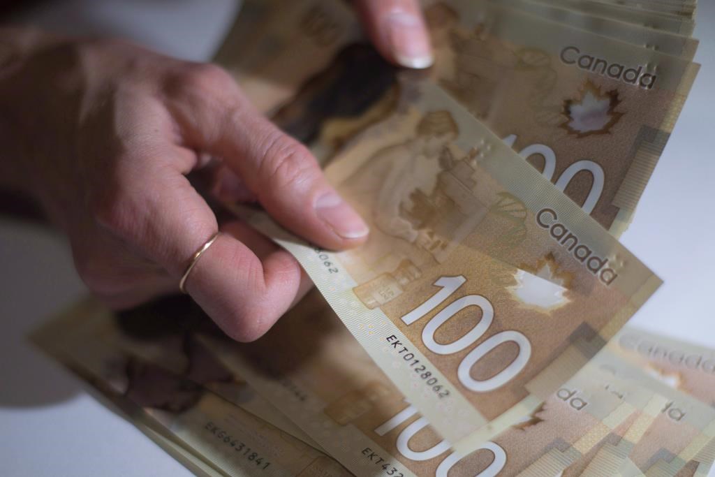 Statistics Canada says the ratio of household debt to disposable income hit a record level in the fourth quarter as mortgage borrowing rose and disposable income fell. Canadian $100 bills are counted in Toronto, Feb. 2, 2016.  THE CANADIAN PRESS/Graeme Roy.