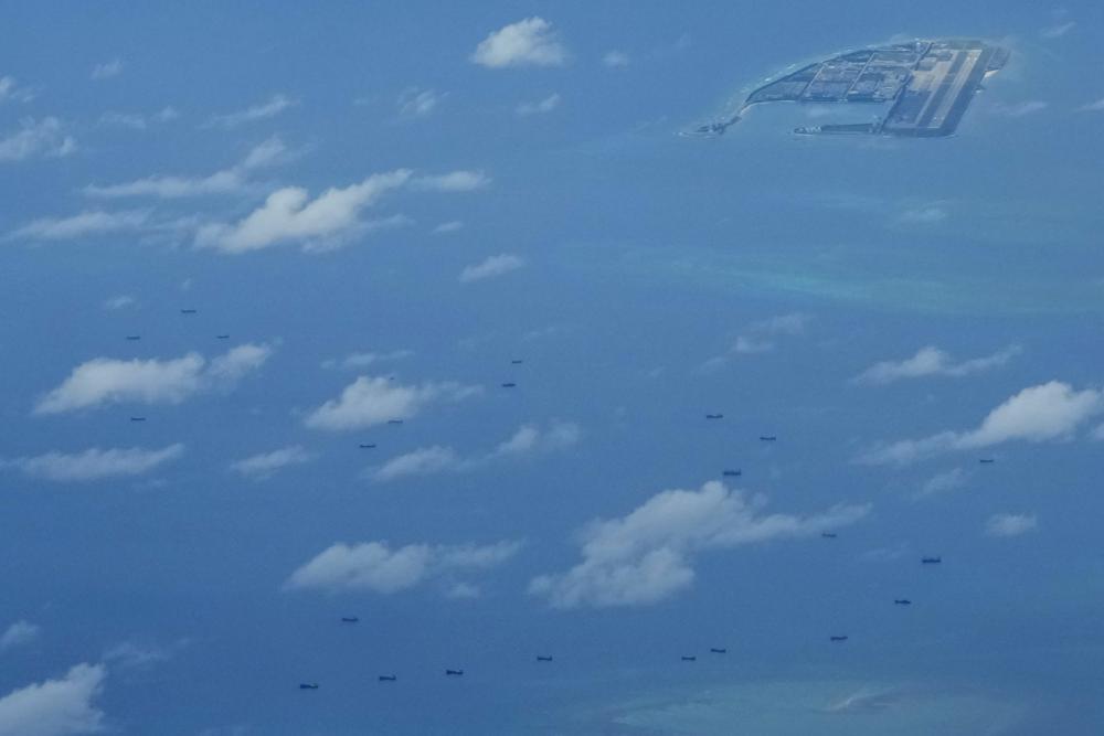 Boats are seen beside Chinese structures and buildings on the man-made Fiery Cross Reef at the Spratlys group of islands in the South China Sea on Sunday March 20, 2022. (AP Photo/Aaron Favila)