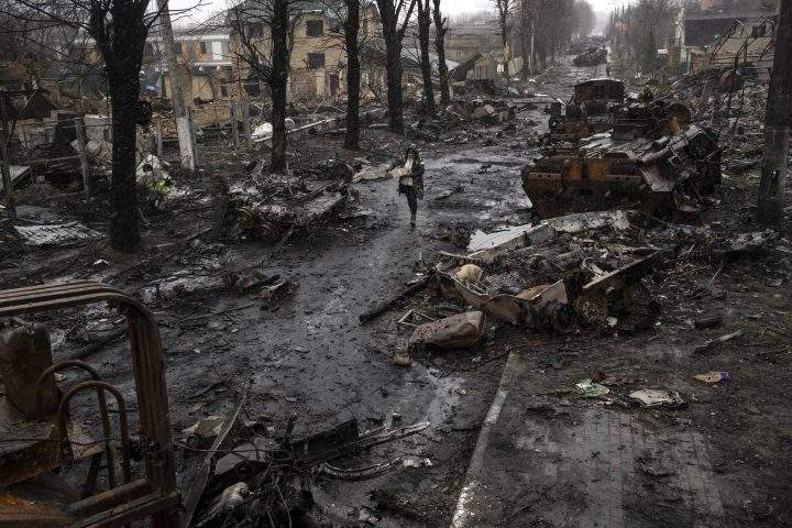 A woman walks amid destroyed Russian tanks in Bucha, in the outskirts of Kyiv, Ukraine, Sunday, April 3, 2022.