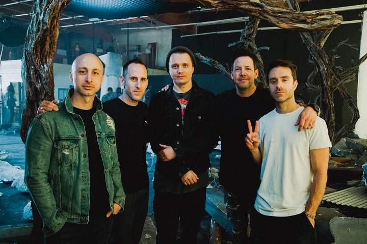 Simple Plan band members, from left to right, Jeff Stinco, Sebastien Lefebvre, Pierre Bouvier and Chuck Comeau pose for a photo on set with Ukrainian filmmaker Jensen Noen, centre, on the set of their new music video, in Los Angeles in an undated handout photo. 