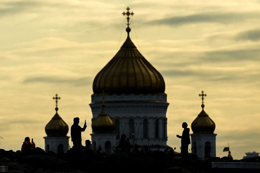 A couple rest in Zaryadye park with the Christ the Savior Cathedral on the background during the sunset in downtown Moscow on April 19, 2022.