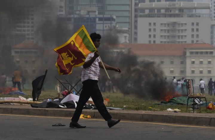 A Sri Lankan government supporter carries a national flag after attacking the anti government protest site outside president’s office in Colombo, Sri Lanka, Monday, May 9, 2022.