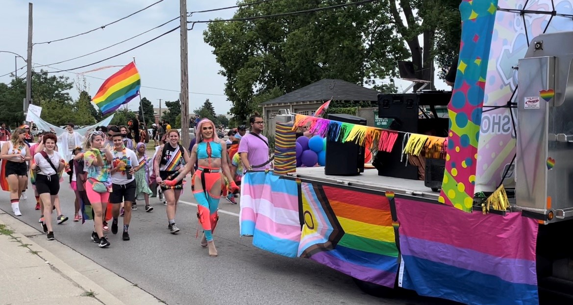 A group dances and cheers as they walk down Dundas St. in London's Pride Parade 2022. 