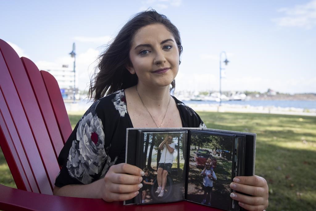 Alyssa Grocutt poses with pictures of her father Kevin who died when she was 11 years old while working at Suncor Energy Inc., in Kingston, Ont., on Wednesday, August 24, 2022. THE CANADIAN PRESS/Lars Hagberg.