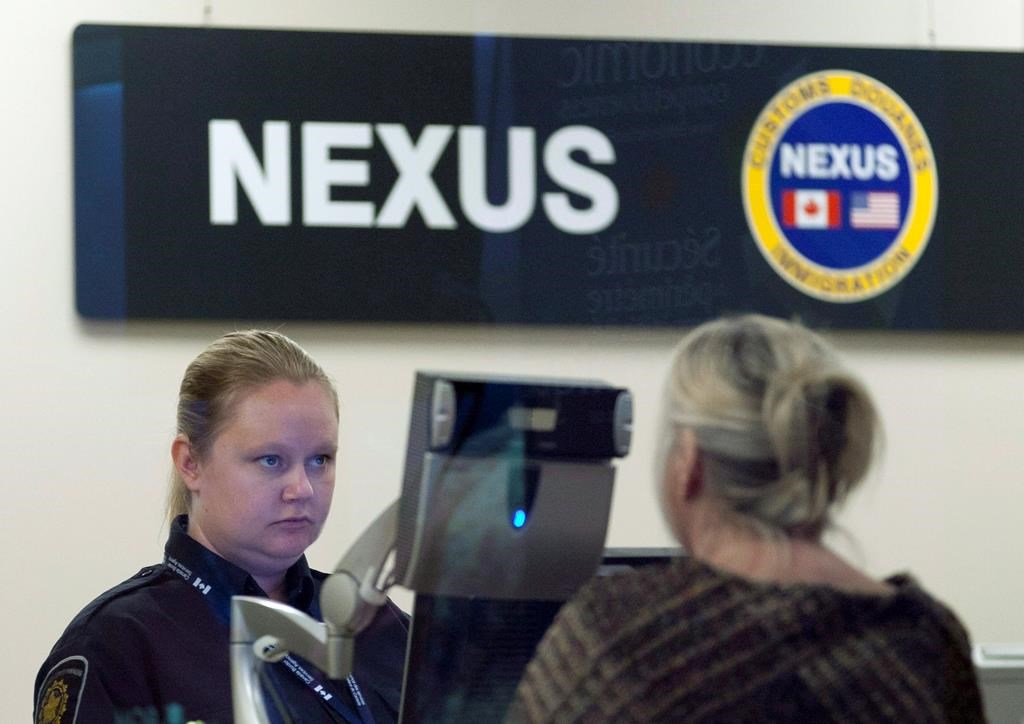 A Canada Border Services Agency officer speaks with a traveller at the Nexus office at the airport in Ottawa, Tuesday, May 8, 2012. 