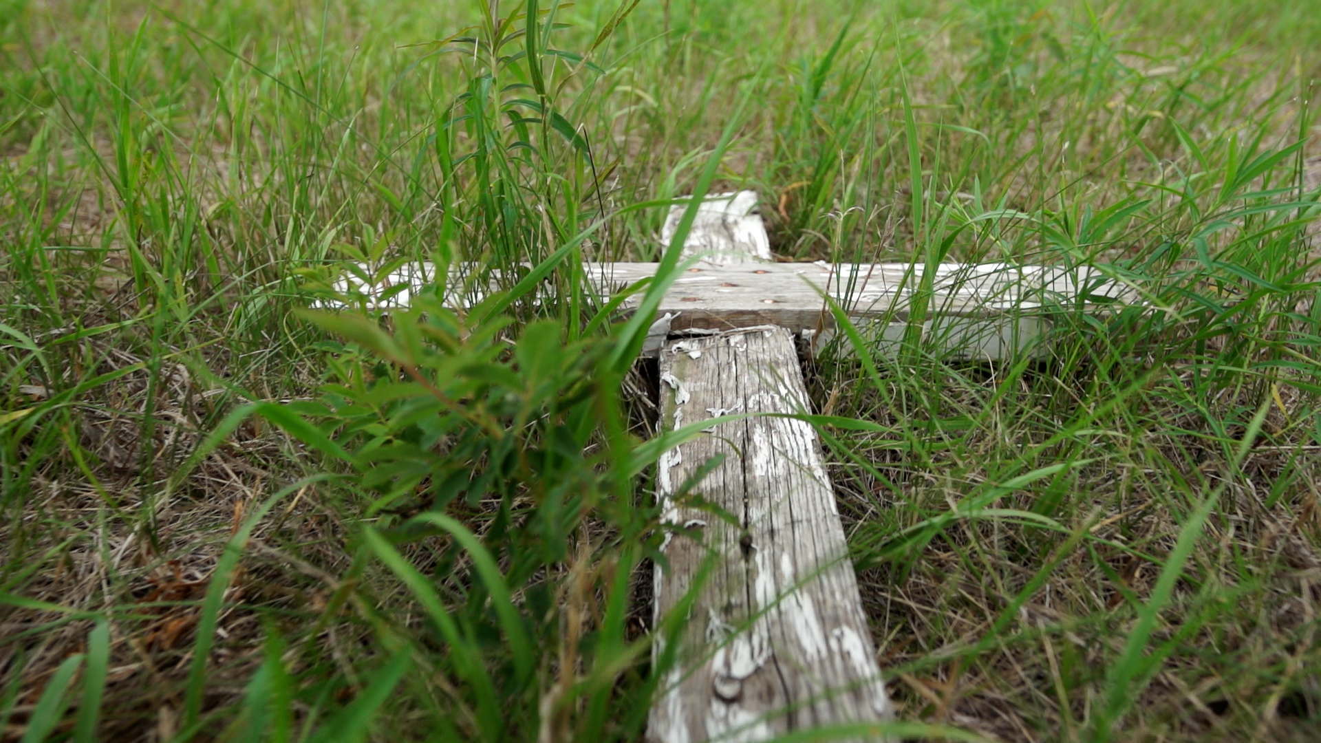 A wooden cross lays flat on the ground in the North Hill Burial Ground north of the former Brandon Residential School site.