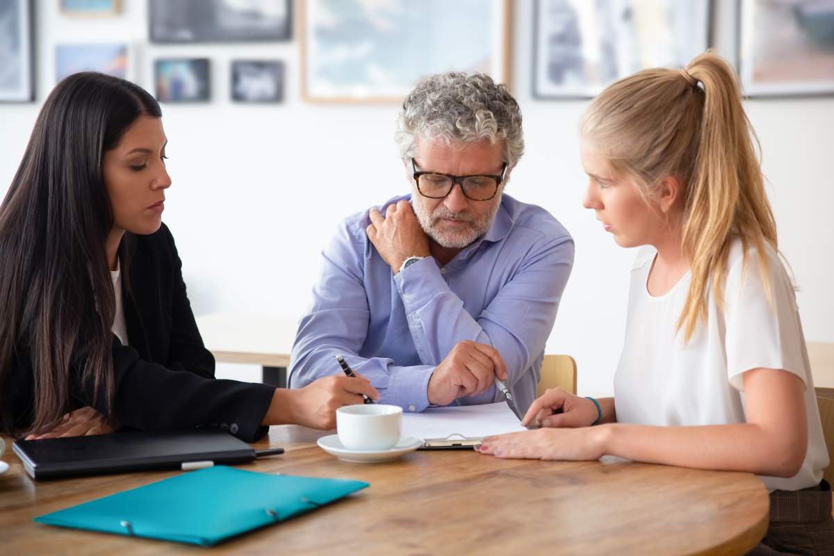 Family legal advisor explaining document details to mature father and adult daughter. Medium shot. Expertise or paperwork concept