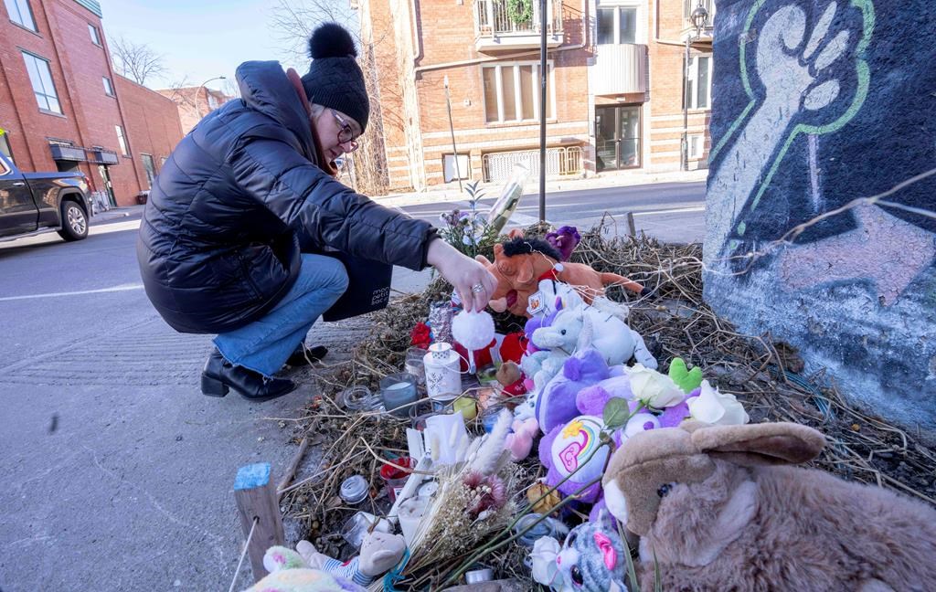 A woman places a candle at a makeshift memorial on the corner where a seven-year-old girl was killed in a hit and run Tuesday, in Montreal, on Wednesday, December 14, 2022.