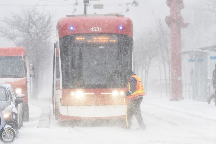 A streetcar driver works to clear ice from a track switch during a snowstorm in Toronto on Friday, December 23, 2022. A winter storm warning is in place for most of southern Ontario.