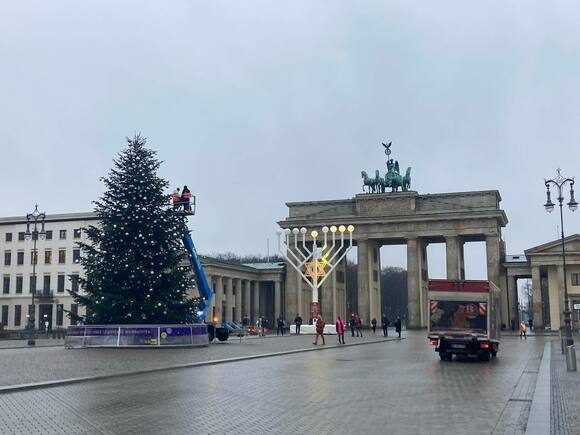 The Christmas tree and hydraulic lifted platform in front of the Brandenburg Gate. A large menorah is seen in the background.