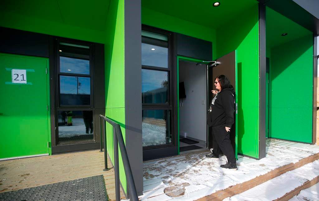 Melissa Stone, co-ordinator of Astum Api Niikinaahk, enters one of the accessible rooms in the tiny house village that just opened for homeless in downtown Winnipeg, on Dec. 1, 2022. The small village of 22 units and a community lodge has been in the works for the past two years and opened to residents this week.