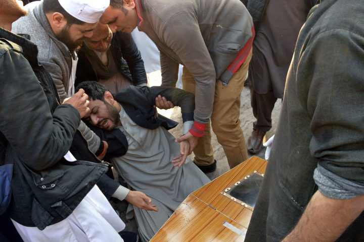 People comfort a man mourning next to the coffin of his family member, who was killed in a suicide bombing inside a mosque in Peshawar, Pakistan, Monday, Jan. 30, 2023.
