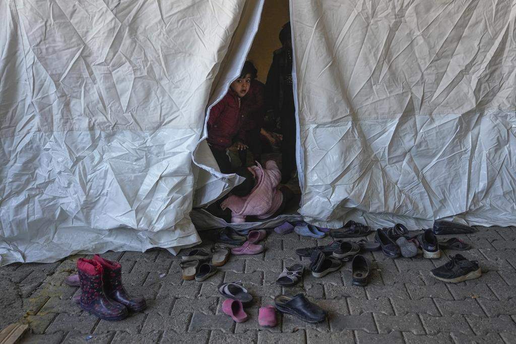 A Syrian child looks on from inside a tent used as a shelter in a public market space in Islahiye District of Gaziantep, southern Turkey, Saturday, Feb. 11, 2023.