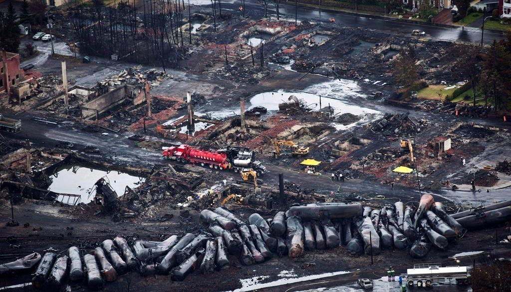 Workers comb through debris after a train derailed Saturday, July 9, 2013 causing explosions of railway cars carrying crude oil in Lac-Mégantic, Quebec. The federal government is moving to acquire land so that it can build a rail bypass in Lac-Mégantic, Que., nearly 10 years after a downtown freight train derailment killed 47 people. THE CANADIAN PRESS/Paul Chiasson.