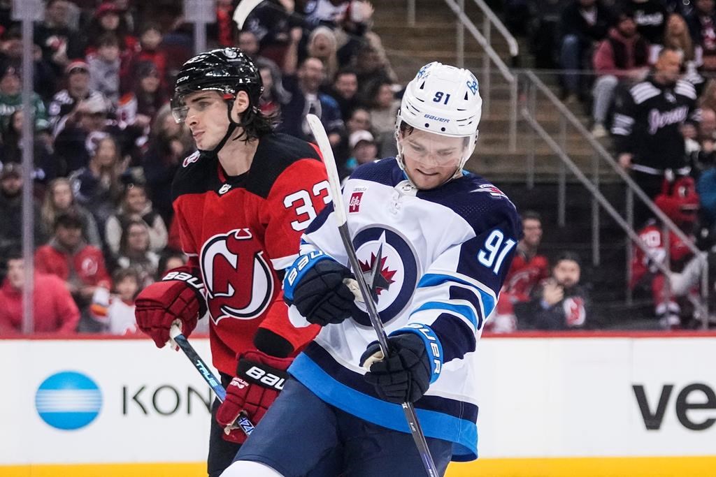 Winnipeg Jets’ Cole Perfetti (91) celebrates as New Jersey Devils’ Ryan Graves (33) skates past after Perfetti scored a goal during the first period of an NHL hockey game on Feb. 19, 2023, in Newark, N.J. THE CANADIAN PRESS/AP-Frank Franklin II