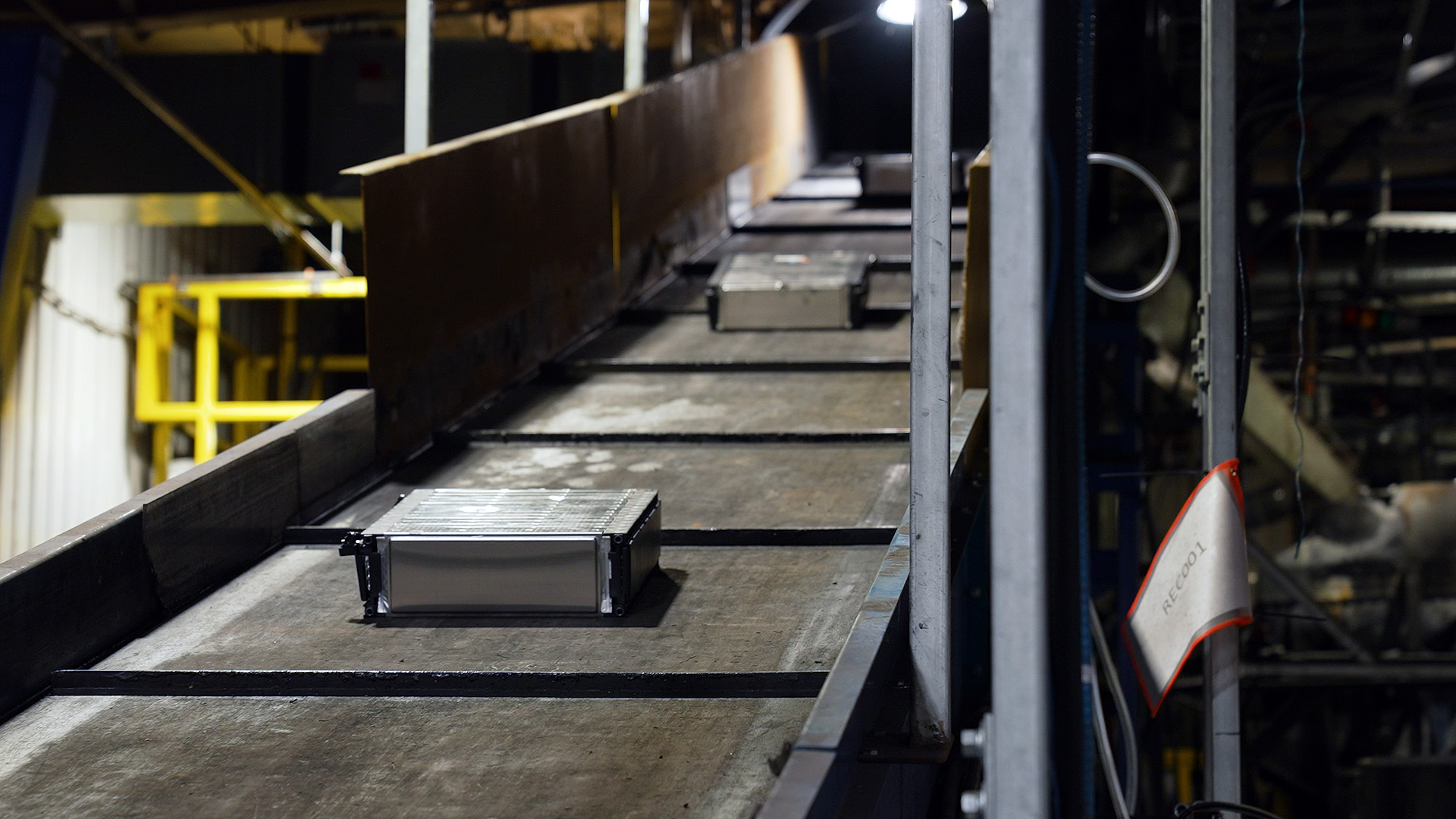 Old or defective electric car battery modules travel up the conveyor. Each will drop into a chemical solution before being shredded.