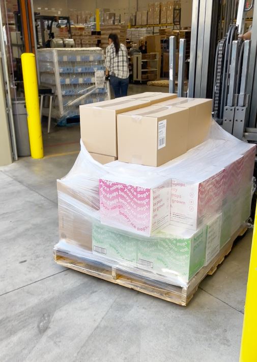 Cases of Hardpops being moved by a forklift.