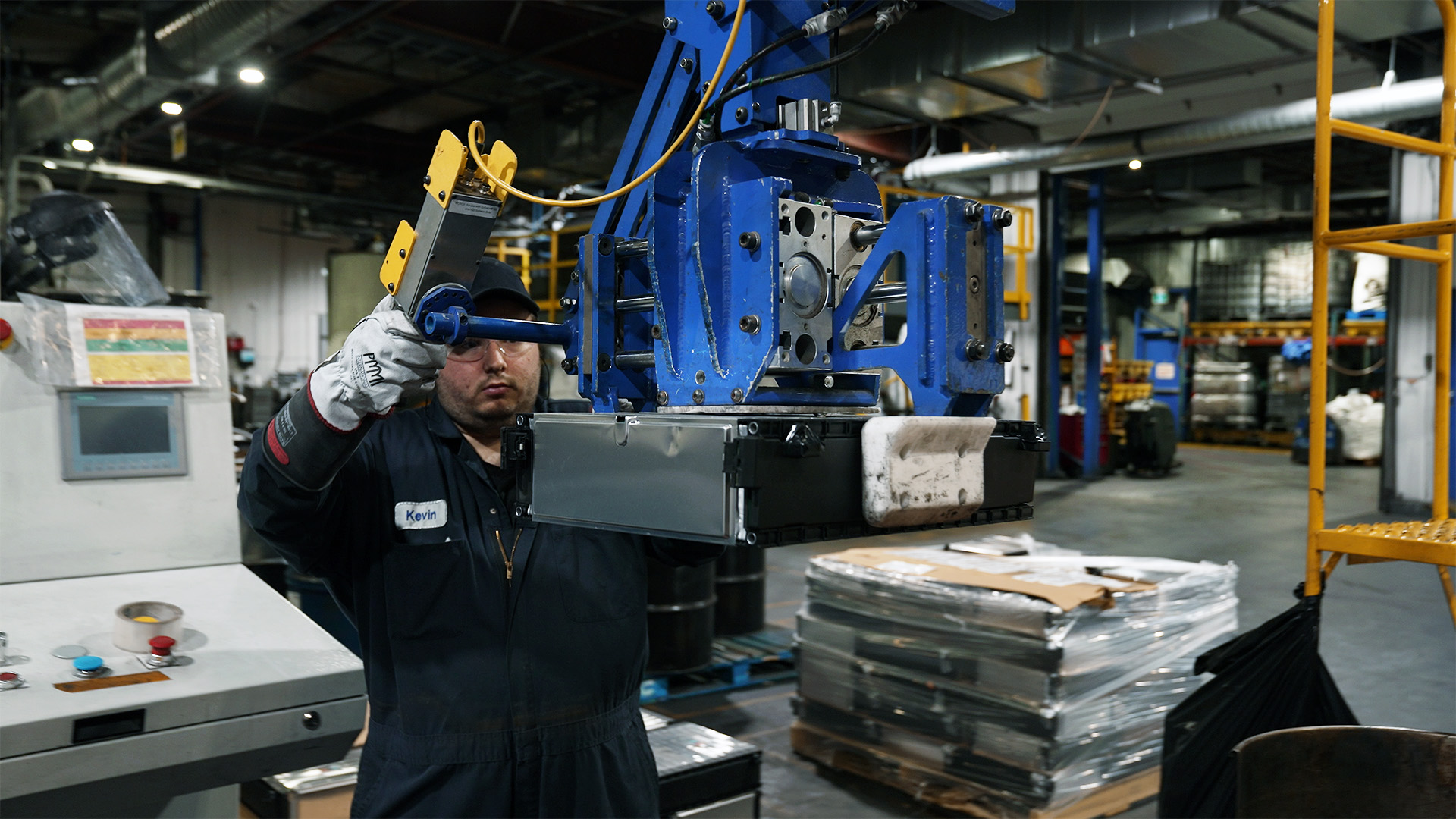 A worker at Li-Cycle's Kingston facility uses a lift assist to move EV battery modules from a skid to the conveyor.