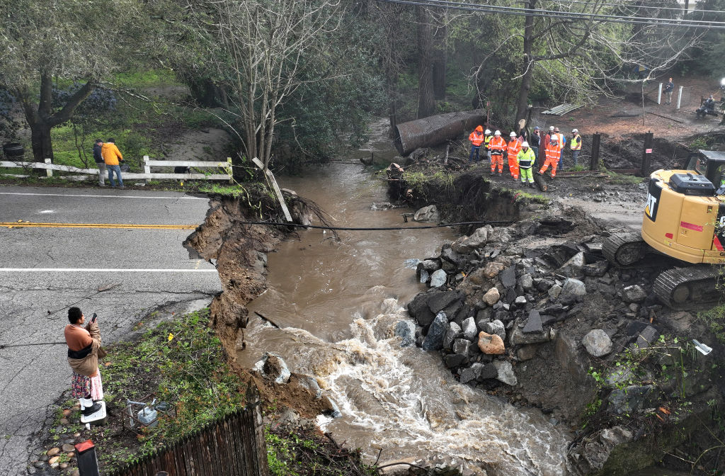 In an aerial view, workers make emergency repairs to a road that was washed out heavy rains on March 10, 2023 in Soquel, Calif.