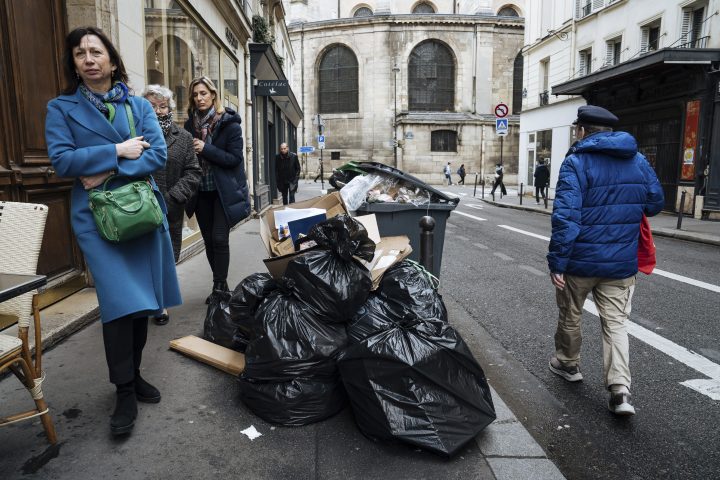 People walk past uncollected garbage in Paris, Monday, March 13, 2023. (AP Photo/Lewis Joly)