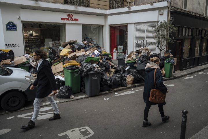 People walk past uncollected garbage in Paris, Monday, March 13, 2023. (AP Photo/Lewis Joly)