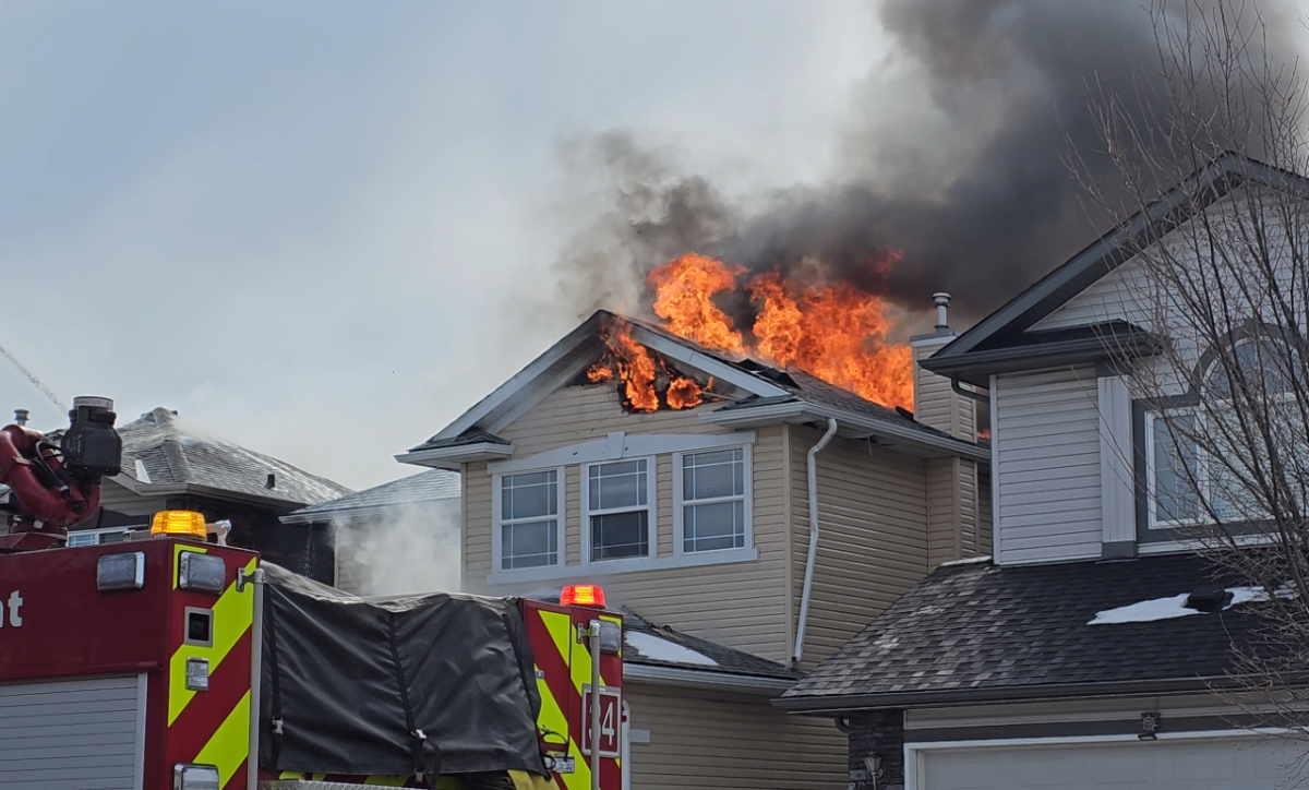 A house in Calgary's Citadel neighbourhood is seen on fire with crews attending, on March 24, 2023.