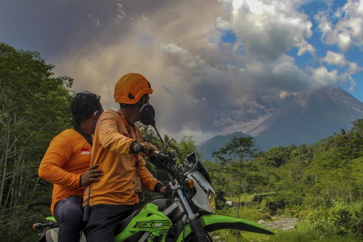 Men watch as Mount Merapi releases volcanic materials during an eruption in Sleman, Indonesia, Saturday, March 11, 2023.