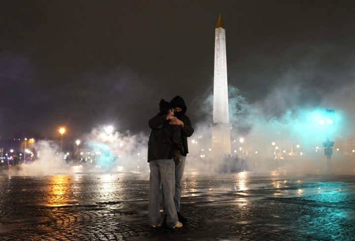 Two people embrace amid a swirl of tear gas silhouetted against the dark night.