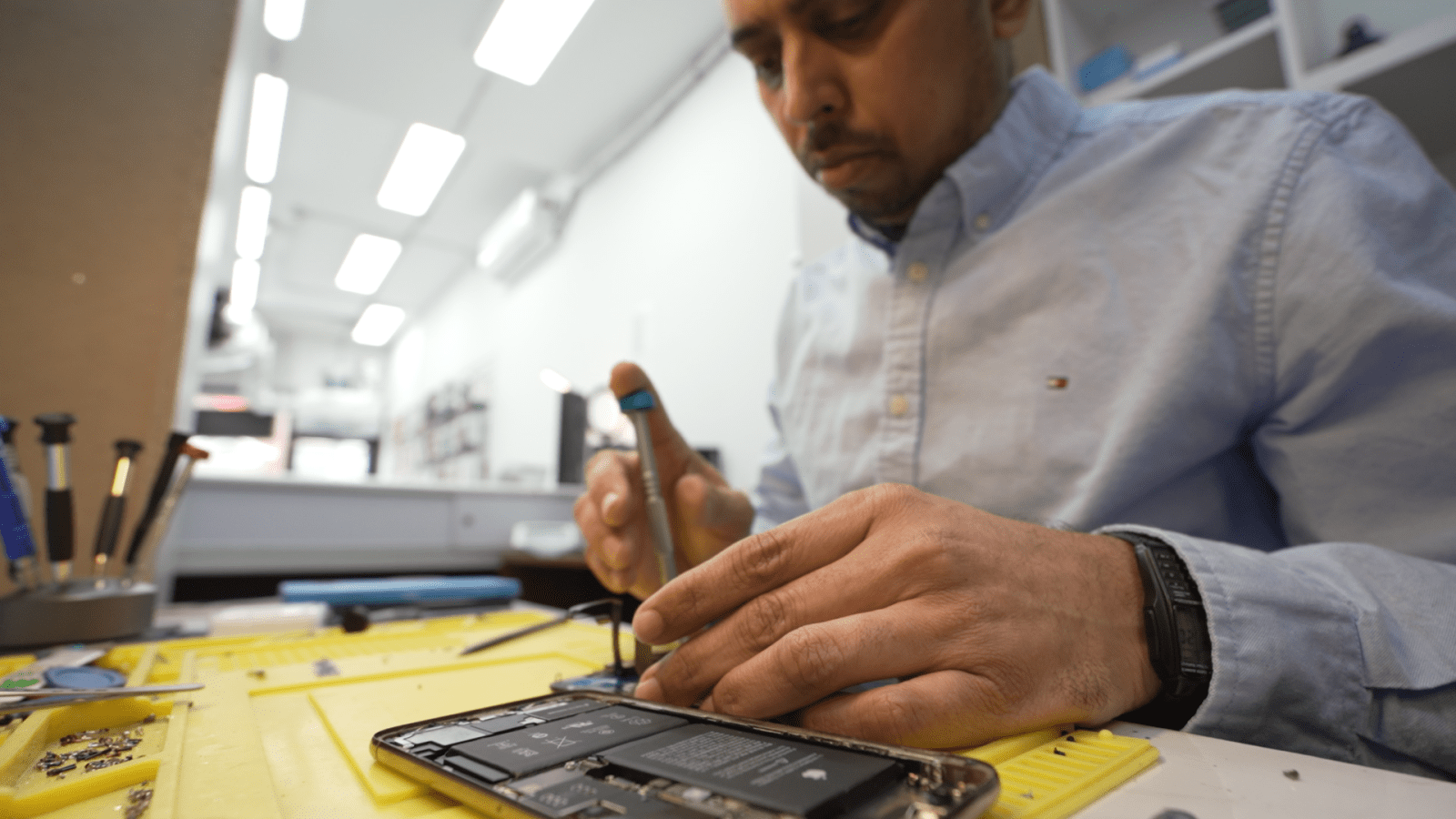 Technician Rayhan Mohammed Siraj repairs an iPhone in his shop, Phone Solutions in Toronto.