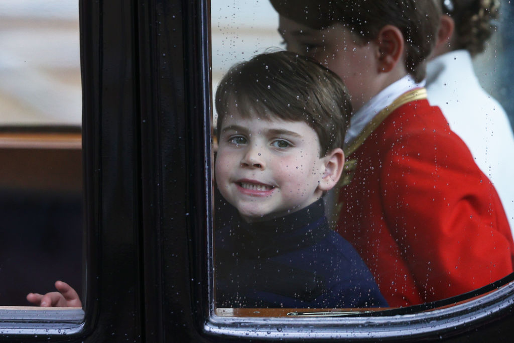 LONDON, ENGLAND – MAY 06: Prince Louis of Wales smiles through the window as he travels with his family back to Buckingham Palace from Westminster Abbey on May 6, 2023 in London, England. (Photo by Adrian Dennis – WPA Pool/Getty Images)