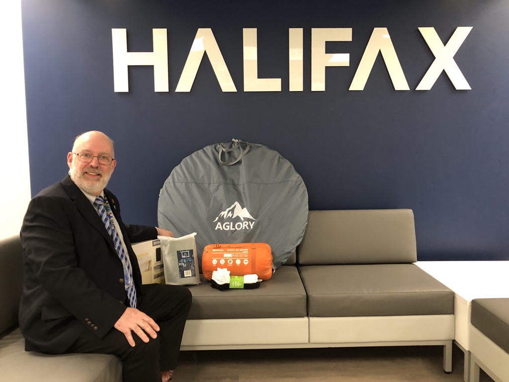 Max Chauvin is Halifax’s Housing and Homelessness Director. He sits next to a kit designed to help those sleeping rough, which includes a tent, sleeping bag, and socks.