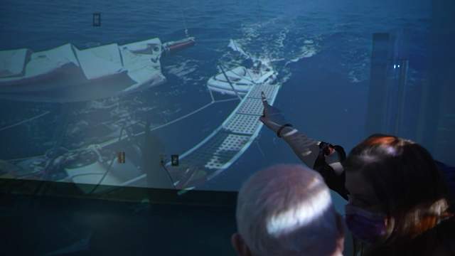 Staff and a patient with dementia looking at a sailboat in water in the 360 virtual room