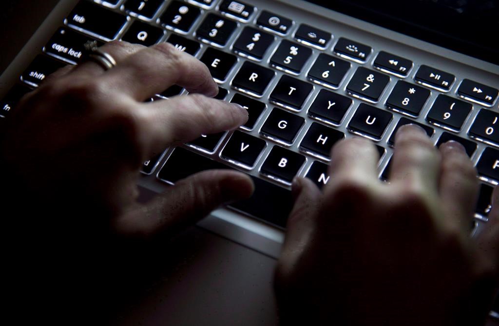 FILE. A woman uses her computer keyboard to type while surfing the internet in North Vancouver, B.C., on Dec. 19, 2012.  