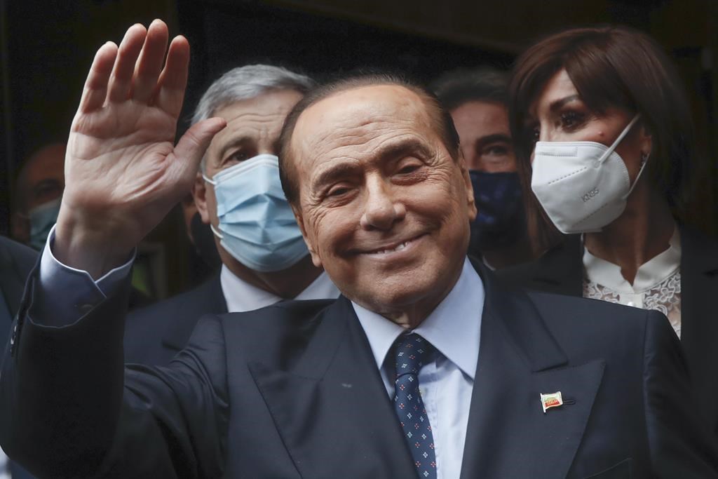 FILE – Former Italian Premier Silvio Berlusconi waves to reporters as he arrives at the Chamber of Deputies to meet Mario Draghi, in Rome, Feb. 9, 2021.