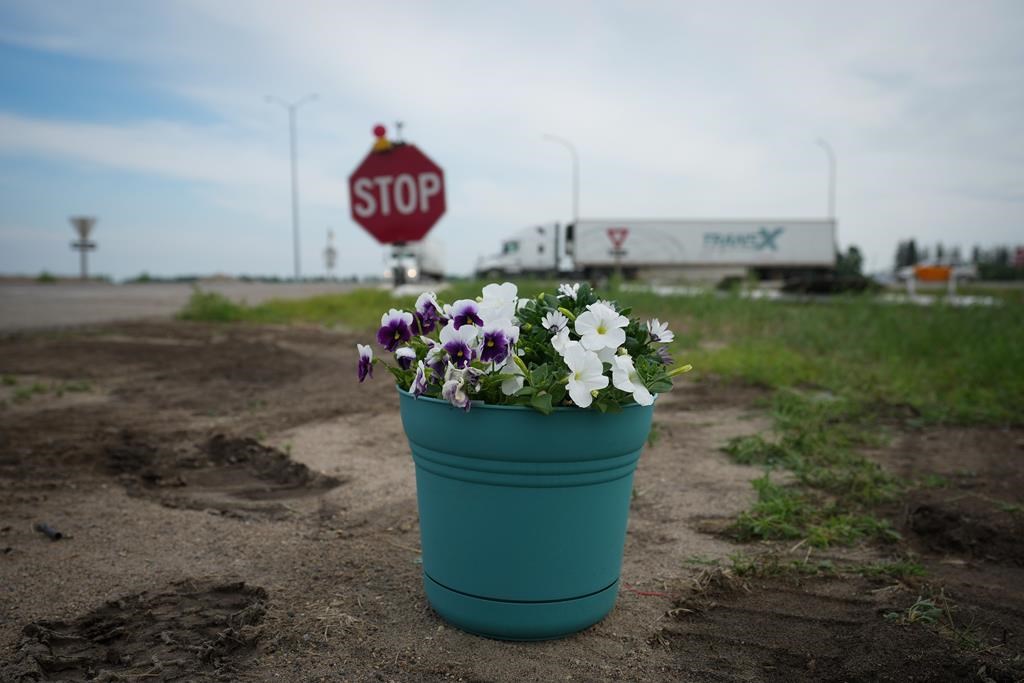 Flowers are seen on the side of the road where the Trans-Canada Highway intersects with Highway 5, west of Winnipeg near Carberry, Man., Friday, June 16, 2023. A semi and a bus carrying seniors collided at the intersection, killing 17 people.