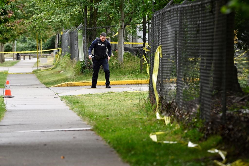 A police officer surveys the scene near the Guru Nanak Sikh Gurdwara Sahib temple after a shooting in Surrey, B.C., Mon. June 19, 2023.