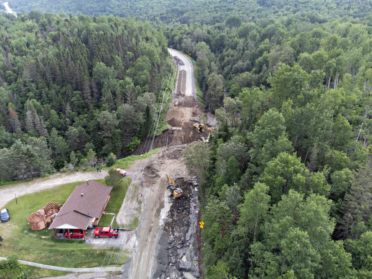 Crews begin repairs to a washed-out section of highway 170 in Rivière-Éternité, Que., Sunday, July 2, 2023. A major landslide caused by heavy rain cut highway 170 between Saguenay, Que., and Saint-Simeon. Two people are missing after they were swept from the road by flood waters.