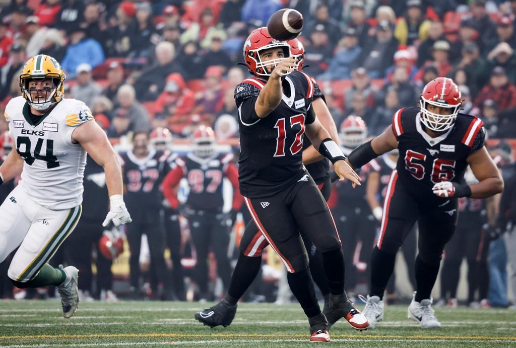 Edmonton Elks defensive lineman Jake Ceresna, left, looks on as Calgary Stampeders quarterback Jake Maier throws the ball during second half CFL football action in Calgary, Alta., Monday, Sept. 4, 2023. The CFL Players' Association says Occupational Health and Safety in Alberta is investigating the CFL's decision to play the Edmonton Elks-Calgary Stampeders game Monday despite smoky conditions in Calgary.
