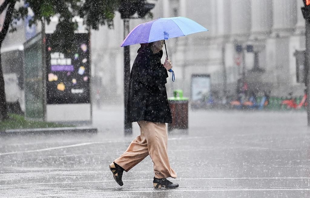 A person walks along a street during heavy rain in Montreal, Saturday, October 7, 2023. Environment Canada has issued a rainfall warning for the province.