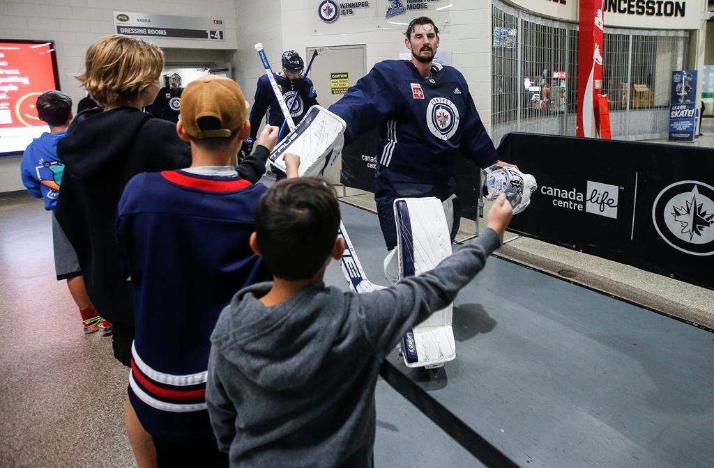 Winnipeg Jets goaltender Connor Hellebuyck (37) high-fives hockey fans as the team changes rinks during day two of their NHL training camp in Winnipeg Sept. 22, 2023. Connor Hellebuyck and Mark Scheifele hope their new contracts show their teammates and fans how much they believe in the Winnipeg Jets.