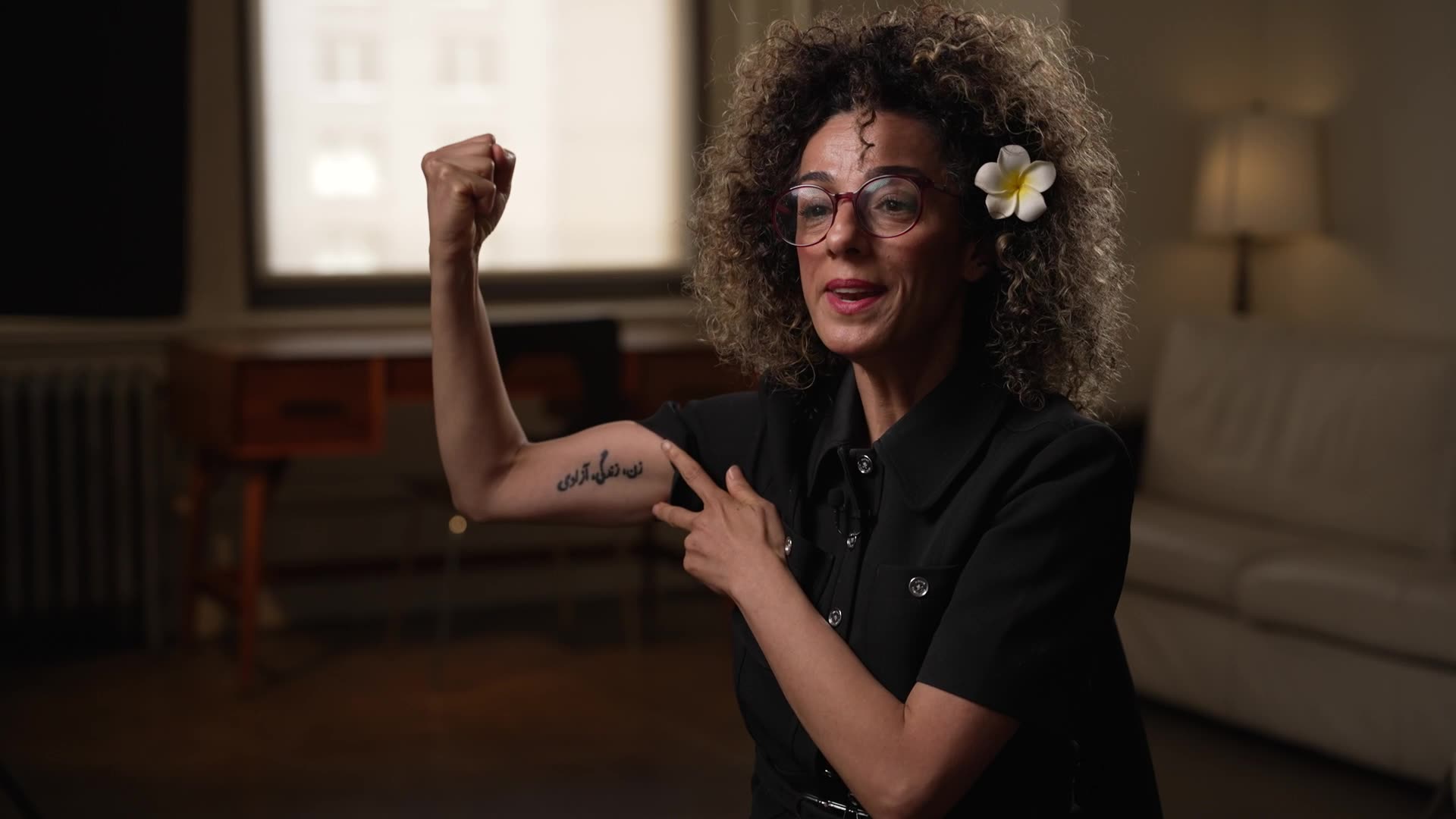 Masih Alinejad flexes her bicep tattooed in Farsi with “Woman, Life, Freedom” — a movement Alinejad forced the world to pay attention to, in defiance of Tehran’s violent suppression of women and girls.
