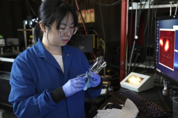Naixin Quin holds a beaker.